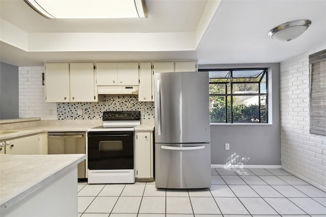 kitchen featuring brick wall, light tile patterned flooring, appliances with stainless steel finishes, and cream cabinets