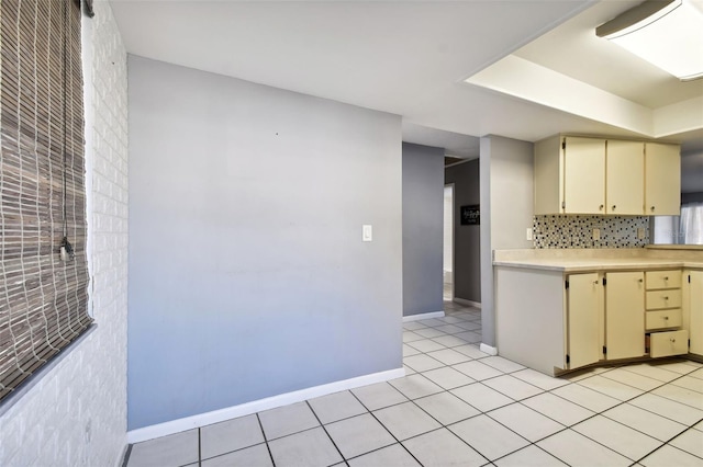 kitchen featuring tasteful backsplash, light tile patterned flooring, and cream cabinetry