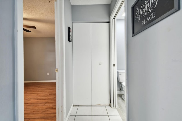 hall with light hardwood / wood-style floors and a textured ceiling