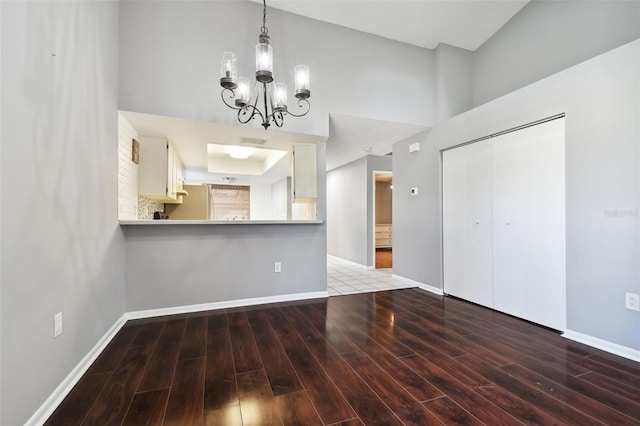 unfurnished dining area featuring an inviting chandelier, a towering ceiling, and hardwood / wood-style flooring