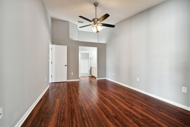 empty room with a high ceiling, ceiling fan, and dark wood-type flooring