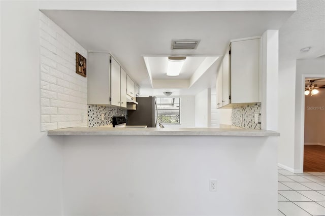 kitchen featuring backsplash, light countertops, visible vents, light tile patterned floors, and freestanding refrigerator