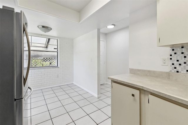 kitchen with light countertops, freestanding refrigerator, baseboards, and light tile patterned floors