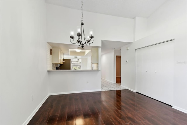 unfurnished dining area with wood finished floors, baseboards, and an inviting chandelier