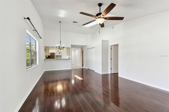 unfurnished living room with baseboards, visible vents, ceiling fan with notable chandelier, wood finished floors, and high vaulted ceiling