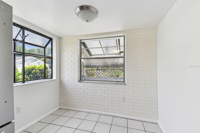 spare room featuring brick wall and baseboards