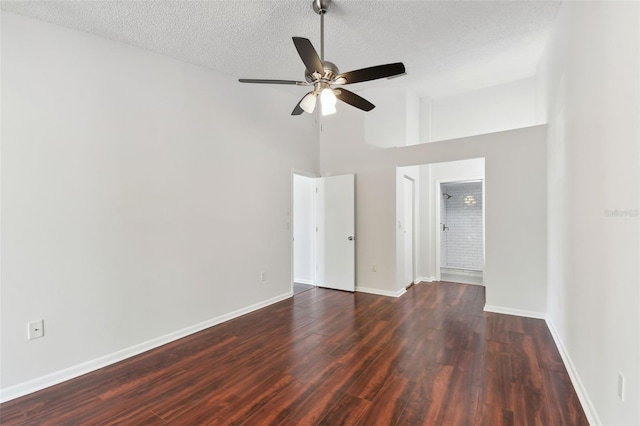 spare room with a ceiling fan, wood finished floors, a textured ceiling, a towering ceiling, and baseboards