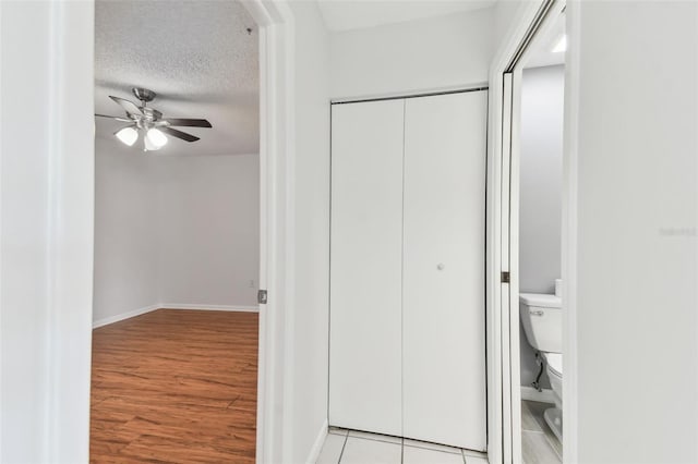 bathroom with a textured ceiling, toilet, baseboards, wood finished floors, and ceiling fan