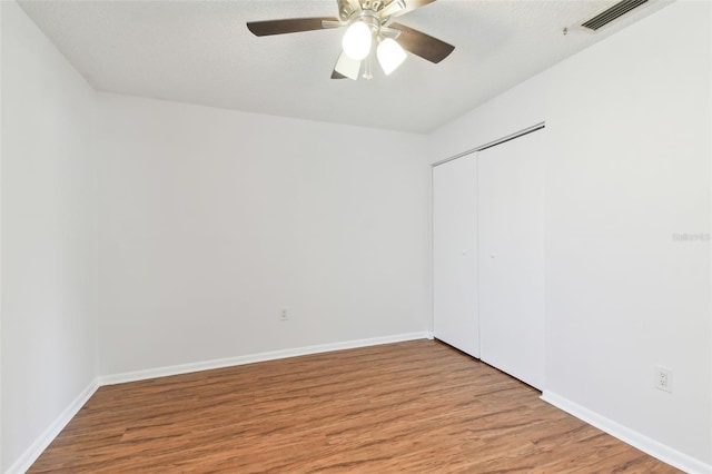 spare room featuring baseboards, a ceiling fan, wood finished floors, and visible vents
