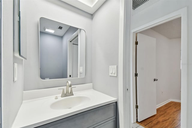 bathroom with baseboards, wood finished floors, visible vents, and vanity
