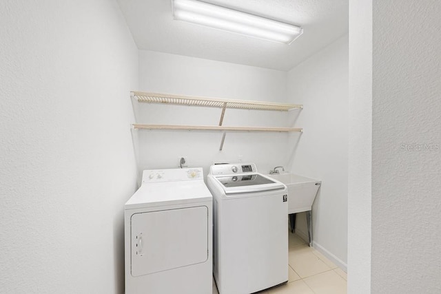 laundry area featuring sink, separate washer and dryer, and light tile patterned flooring