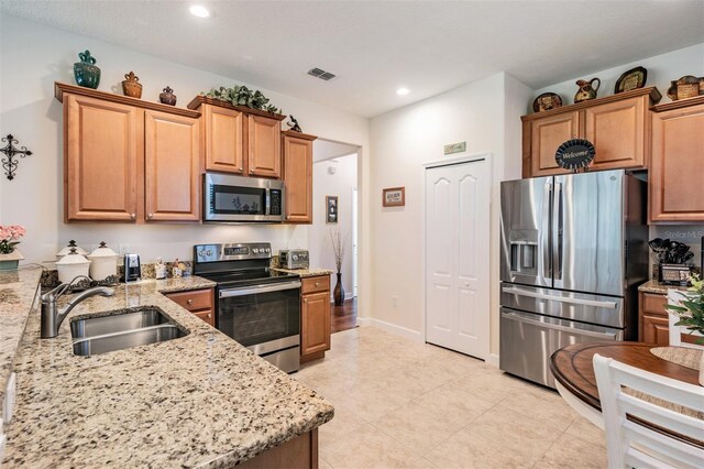 kitchen featuring sink, light stone countertops, and stainless steel appliances