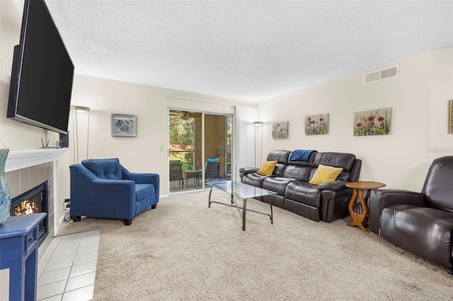 living room with light carpet, a textured ceiling, and a tile fireplace