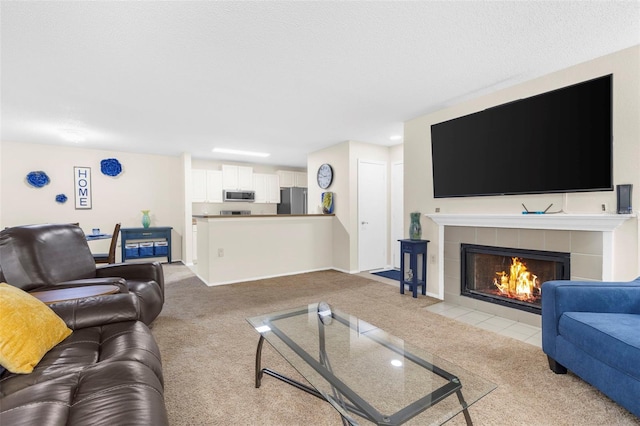 living room with a tiled fireplace, light carpet, and a textured ceiling