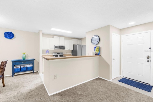 kitchen with stainless steel appliances, white cabinetry, light colored carpet, and kitchen peninsula