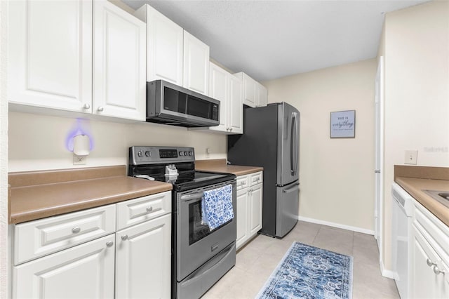 kitchen with stainless steel appliances, white cabinetry, and light tile patterned floors