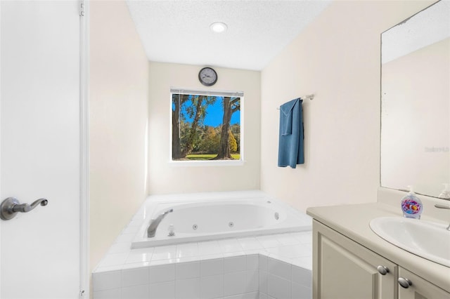 bathroom with vanity, a relaxing tiled tub, and a textured ceiling