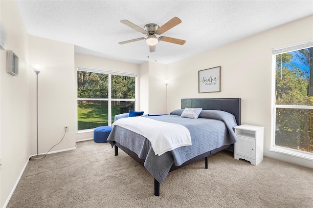 carpeted bedroom featuring multiple windows, ceiling fan, and a textured ceiling