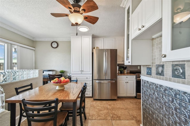 kitchen with decorative backsplash, white cabinetry, and stainless steel refrigerator