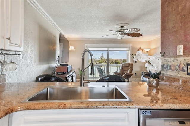 kitchen with white cabinets, a textured ceiling, crown molding, and sink