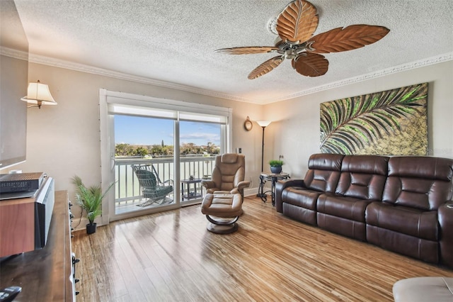 living room with ceiling fan, ornamental molding, a textured ceiling, and light wood-type flooring