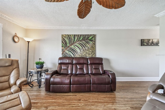 living room featuring ceiling fan, crown molding, wood-type flooring, and a textured ceiling