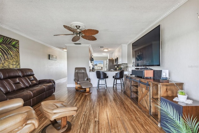 living room with a textured ceiling, dark hardwood / wood-style flooring, ceiling fan, and ornamental molding