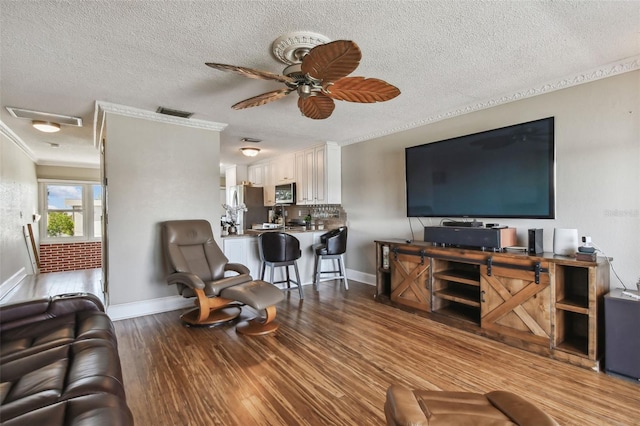 living room with a textured ceiling, light hardwood / wood-style flooring, ceiling fan, and crown molding