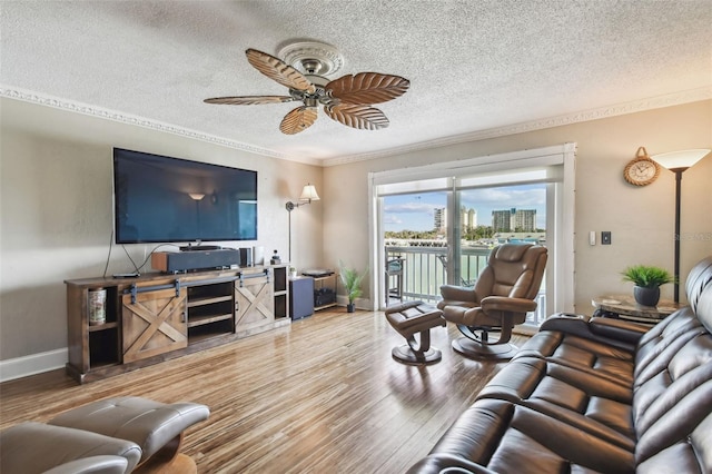 living room with wood-type flooring, a textured ceiling, ceiling fan, and crown molding