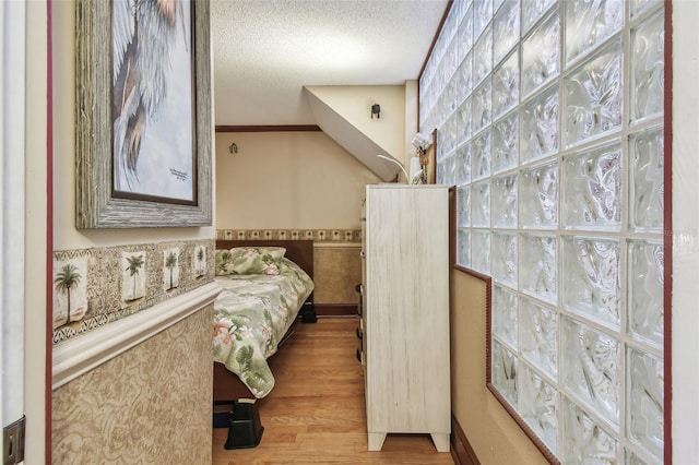 bedroom featuring crown molding, a textured ceiling, and light hardwood / wood-style flooring