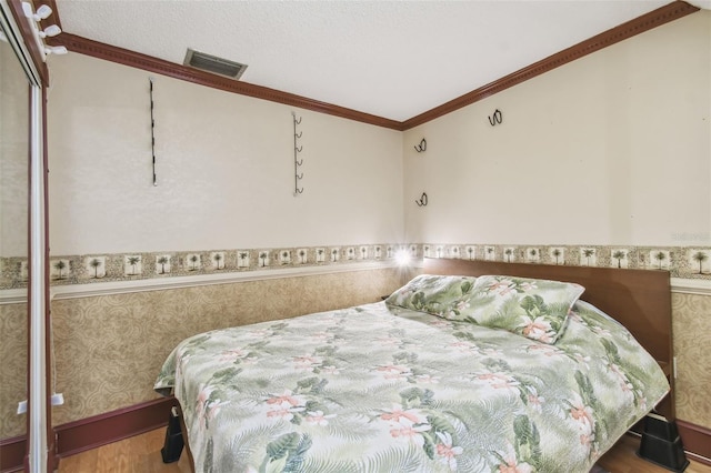 bedroom with hardwood / wood-style floors, ornamental molding, a textured ceiling, and a closet