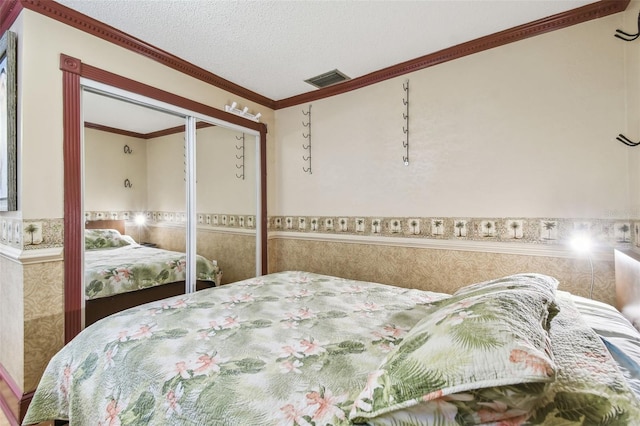 bedroom featuring a closet, a textured ceiling, and ornamental molding