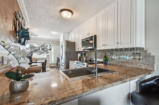 143 94th Ave Unit 2, Treasure Island, FL 33706 - kitchen with a textured ceiling, backsplash, white cabinetry, freestanding refrigerator, and stone countertops