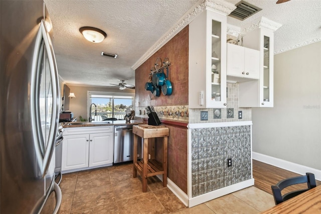 143 94th Ave Unit 2, Treasure Island, FL 33706 - kitchen with stainless steel appliances, a textured ceiling, ceiling fan, white cabinetry, and backsplash