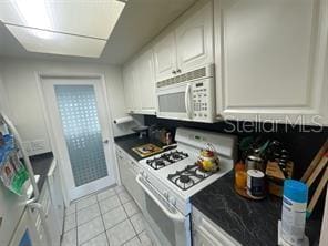 kitchen with white cabinetry, white appliances, and light tile patterned floors