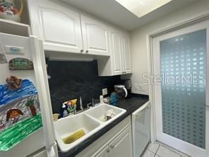 kitchen with light tile patterned floors, white cabinets, white appliances, and sink