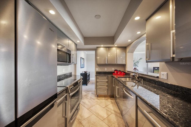 kitchen featuring sink, gray cabinets, dark stone countertops, light tile patterned floors, and appliances with stainless steel finishes