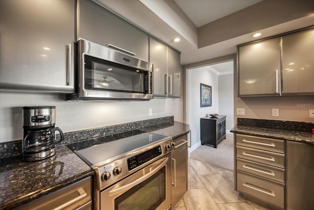 kitchen with dark stone counters, gray cabinets, ornamental molding, and appliances with stainless steel finishes