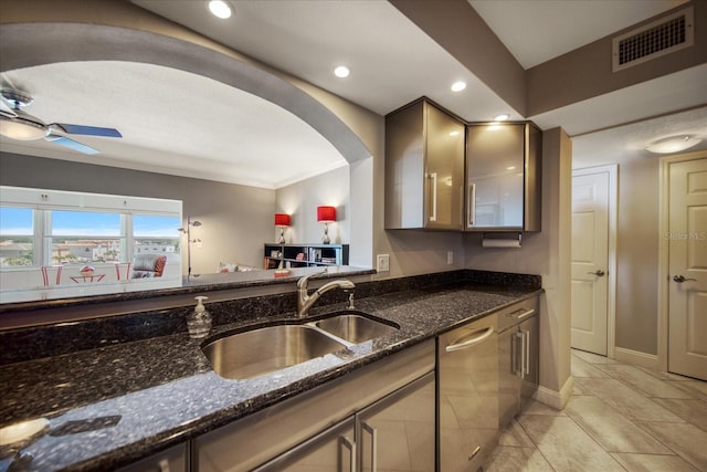 kitchen featuring dark stone counters, ceiling fan, crown molding, sink, and dishwasher