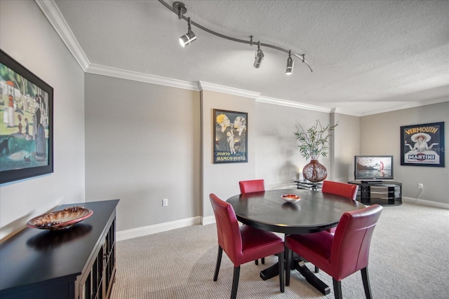 carpeted dining area featuring rail lighting, a textured ceiling, and ornamental molding