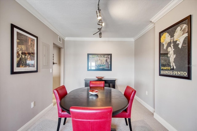 dining area featuring carpet, a textured ceiling, rail lighting, and ornamental molding