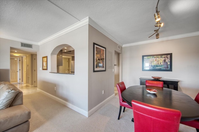 dining area with carpet floors, a textured ceiling, and ornamental molding