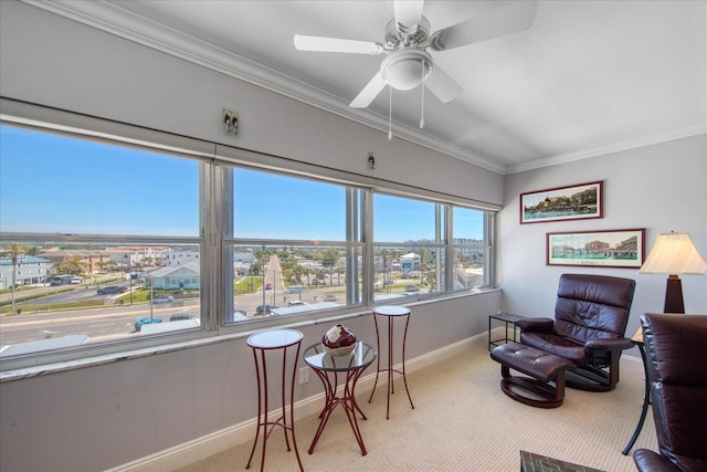 living area with a wealth of natural light, crown molding, ceiling fan, and light colored carpet