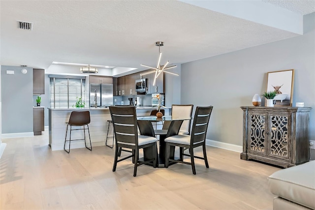 dining room featuring light hardwood / wood-style floors, a textured ceiling, and a chandelier