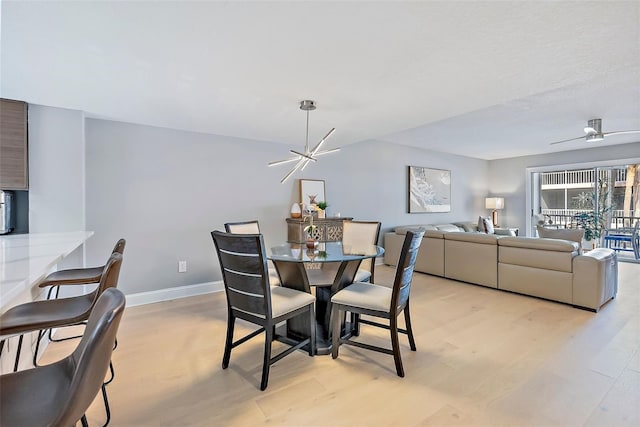 dining room with ceiling fan with notable chandelier and light hardwood / wood-style flooring