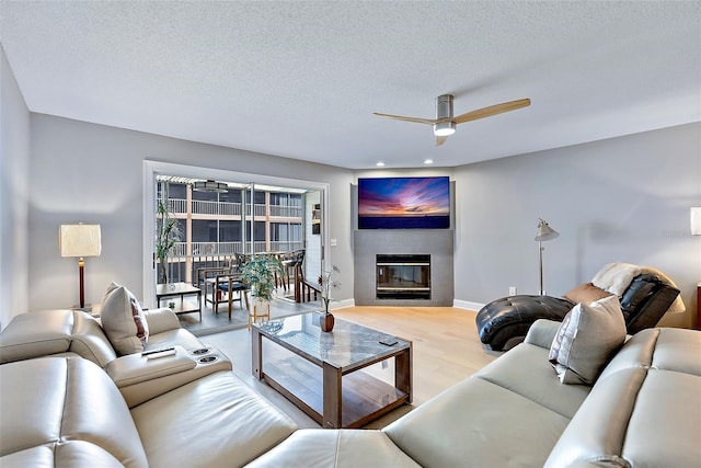 living room featuring ceiling fan, a textured ceiling, and light hardwood / wood-style flooring