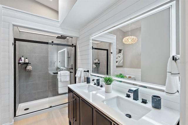 bathroom with vanity, a shower with door, wooden walls, wood-type flooring, and an inviting chandelier