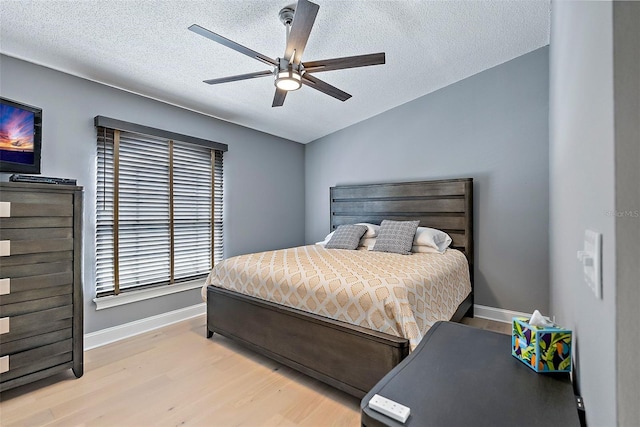 bedroom with ceiling fan, a textured ceiling, and light hardwood / wood-style flooring