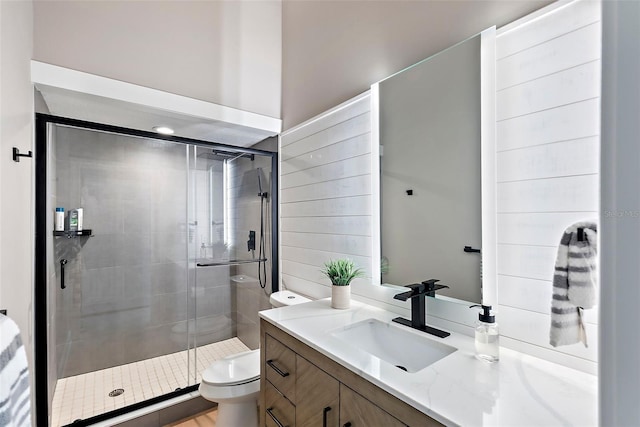 bathroom with a shower with door, vanity, and toilet