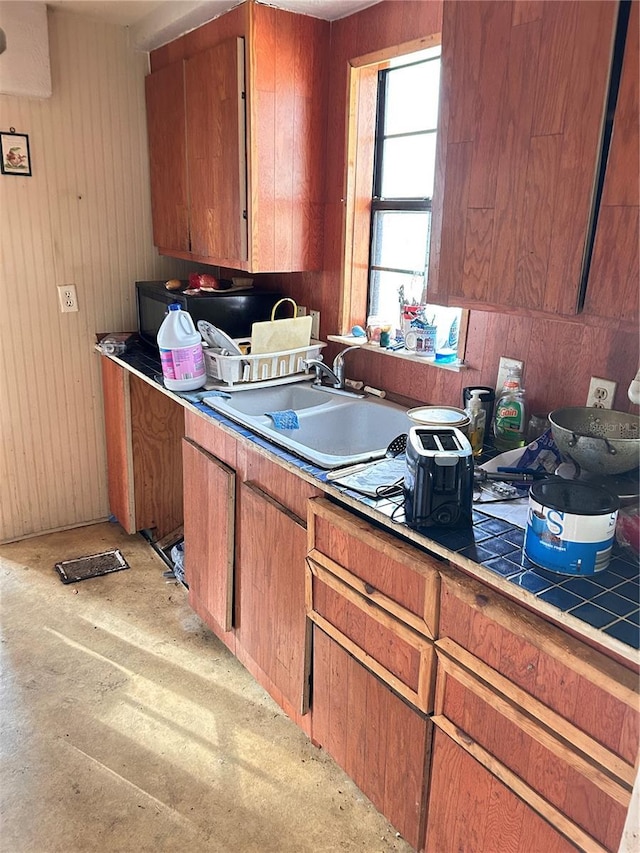 kitchen with tile countertops, wooden walls, and sink